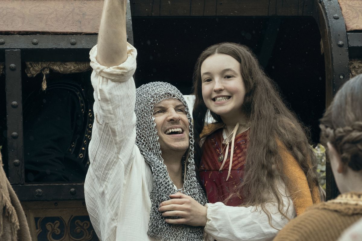 a man wearing a chainmail snood holds up a young teenage girl