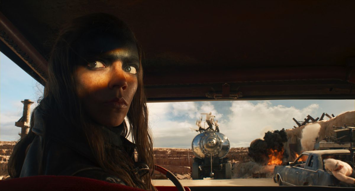 Anya Taylor-Joy as Furiosa in Furiosa, the Mad Max spinoff movie, looking back toward the camera with grease on her forehead. 