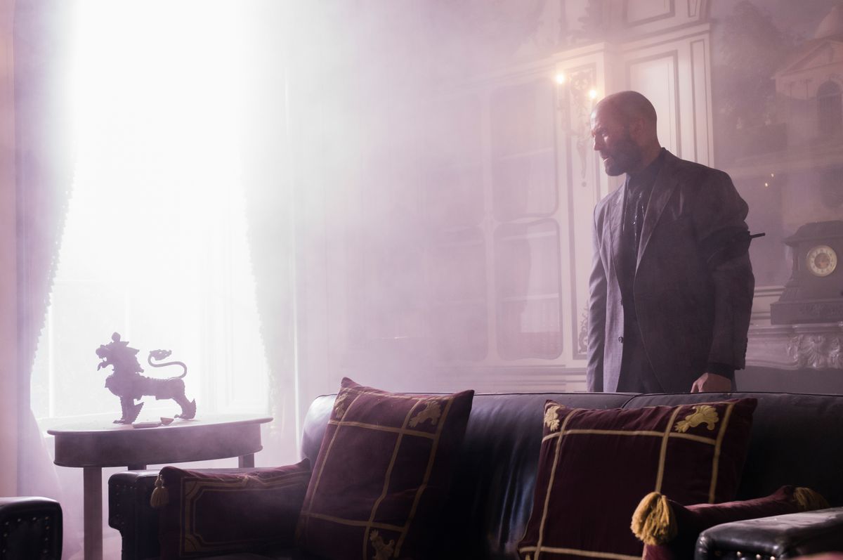 Jason Statham smolders in a brightly lit room with fancy furniture and decorations in The Beekeeper.
