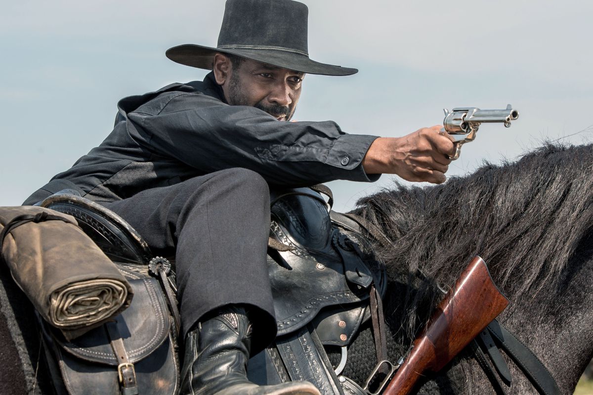Denzel Washington points a gun while riding a horse in The Magnificent Seven