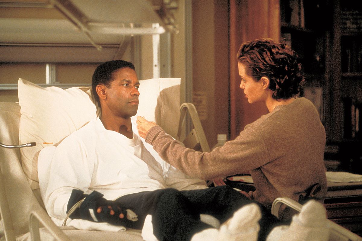 Angelina Jolie sits on a hospital bed that Denzel Washington is lying in, in The Bone Collector.