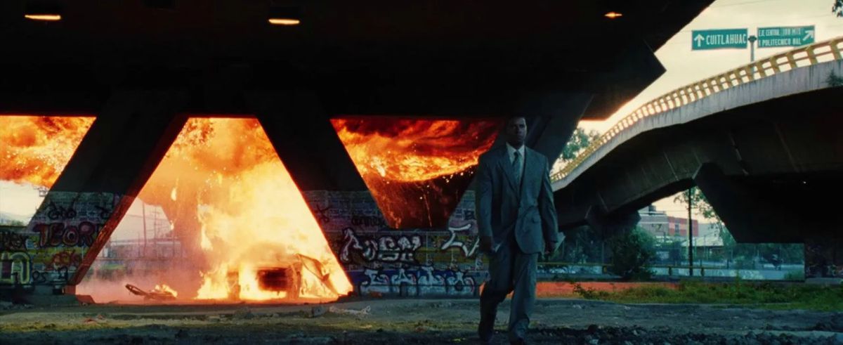 Creasy walking away from a car engulfed in flames beneath a highway underpass in Man on Fire.