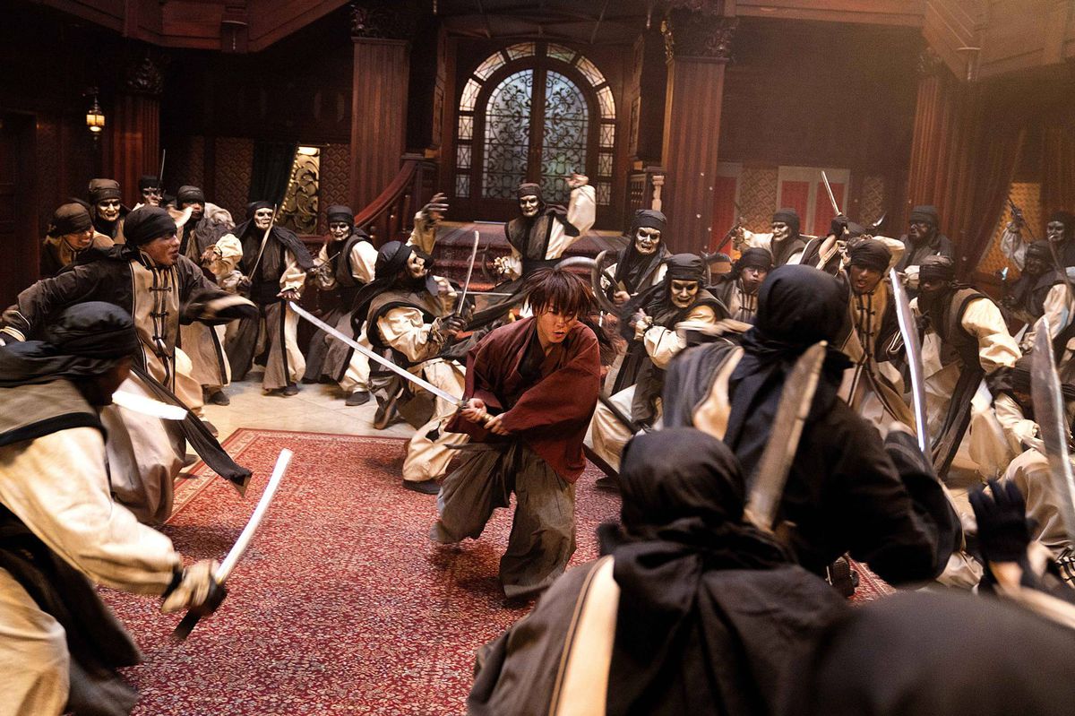 Kenshin charges through a room of masked and unmasked warriors in Rurouni Kenshin: The Final