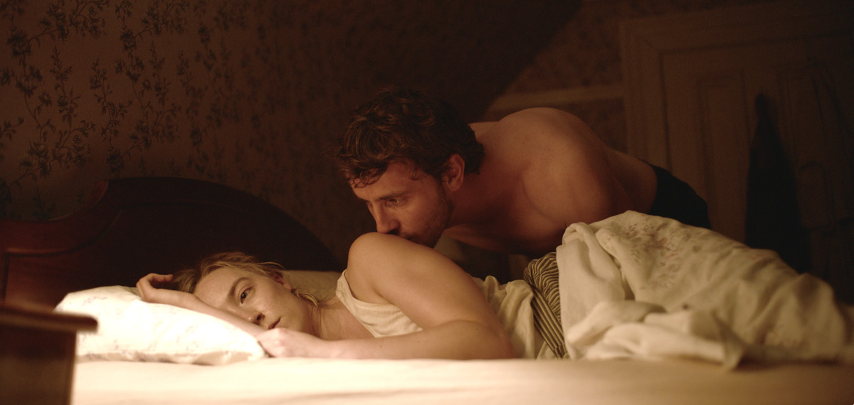 Hen (Saoirse Ronan) lies in bed looking despondent while Junior (Paul Mescal) kisses her shoulder tentatively