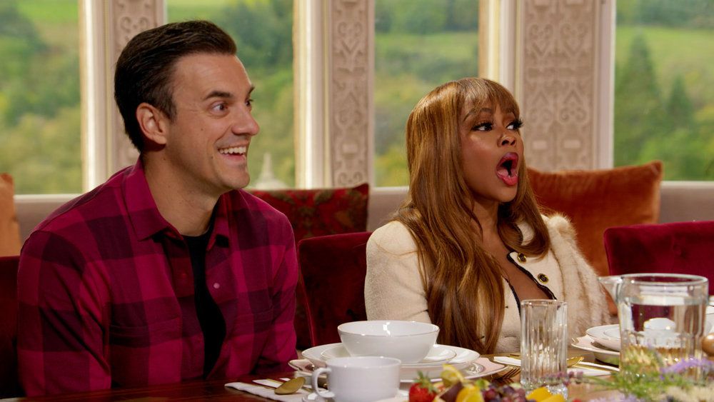 Dan Gheesling and Phaedra Parks sit at a breakfast table in a still from The Traitors. Dan has a slightly surprised smile on his face, while Phaedra has her mouth open in shock.