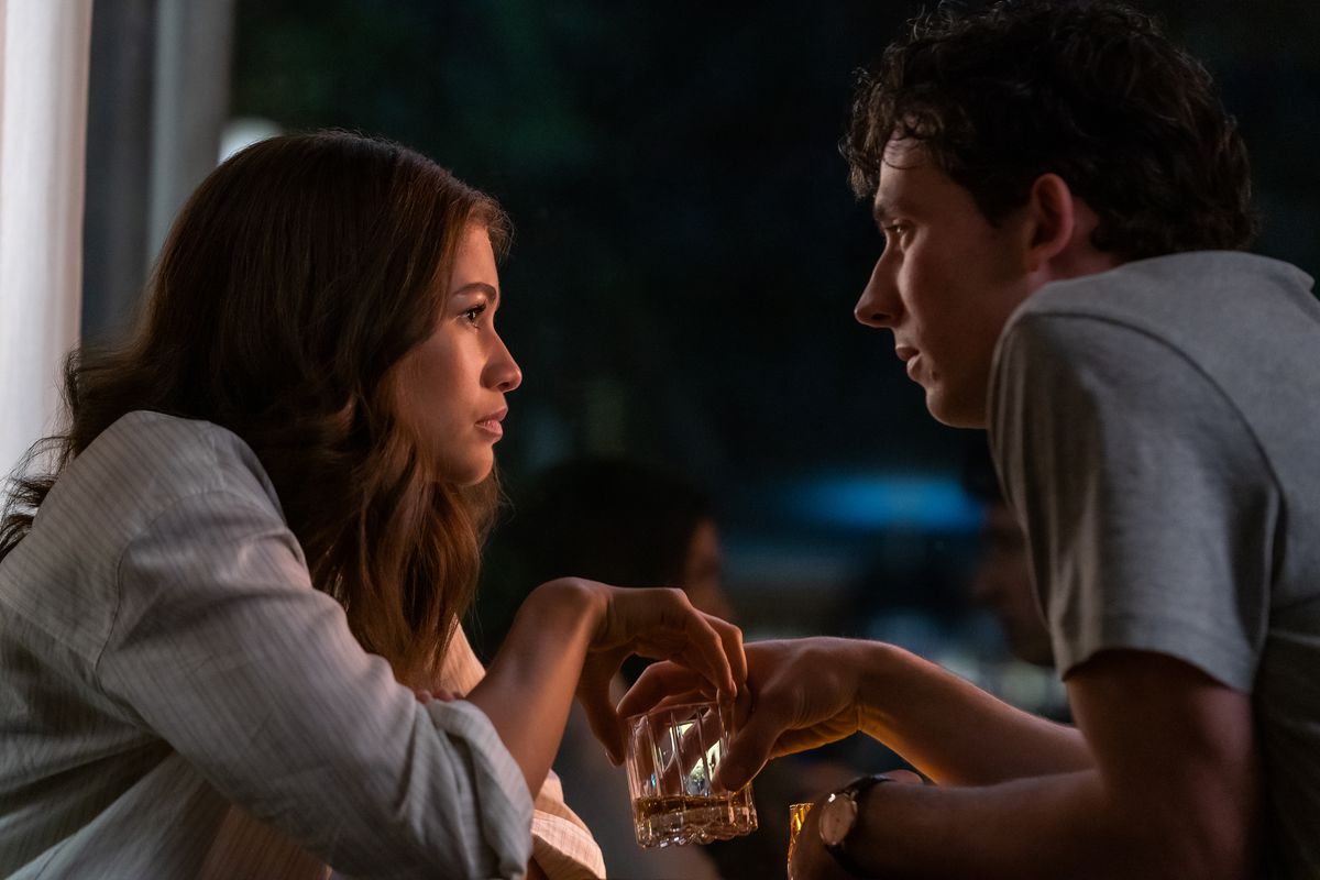 Tennis star Tashi (Zendaya) sits outdoors at night, sharing a drink with Patrick (Josh O’Connor) in Luca Guadagnino’s Challengers