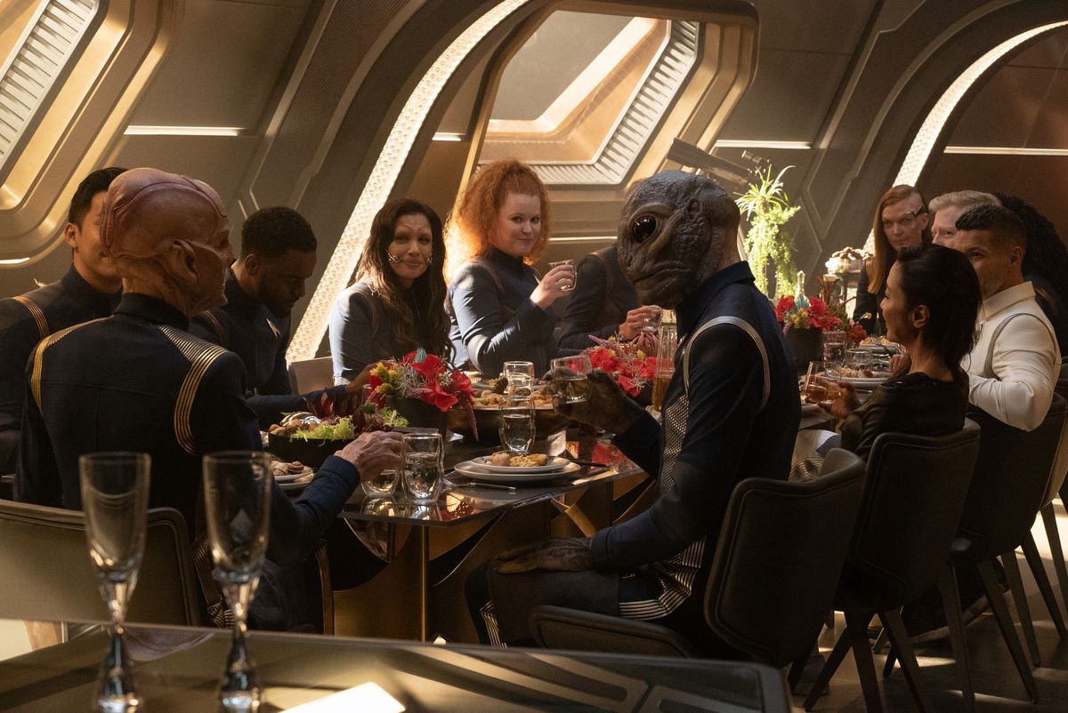 The Discovery crew sitting at a table eating a big meal 