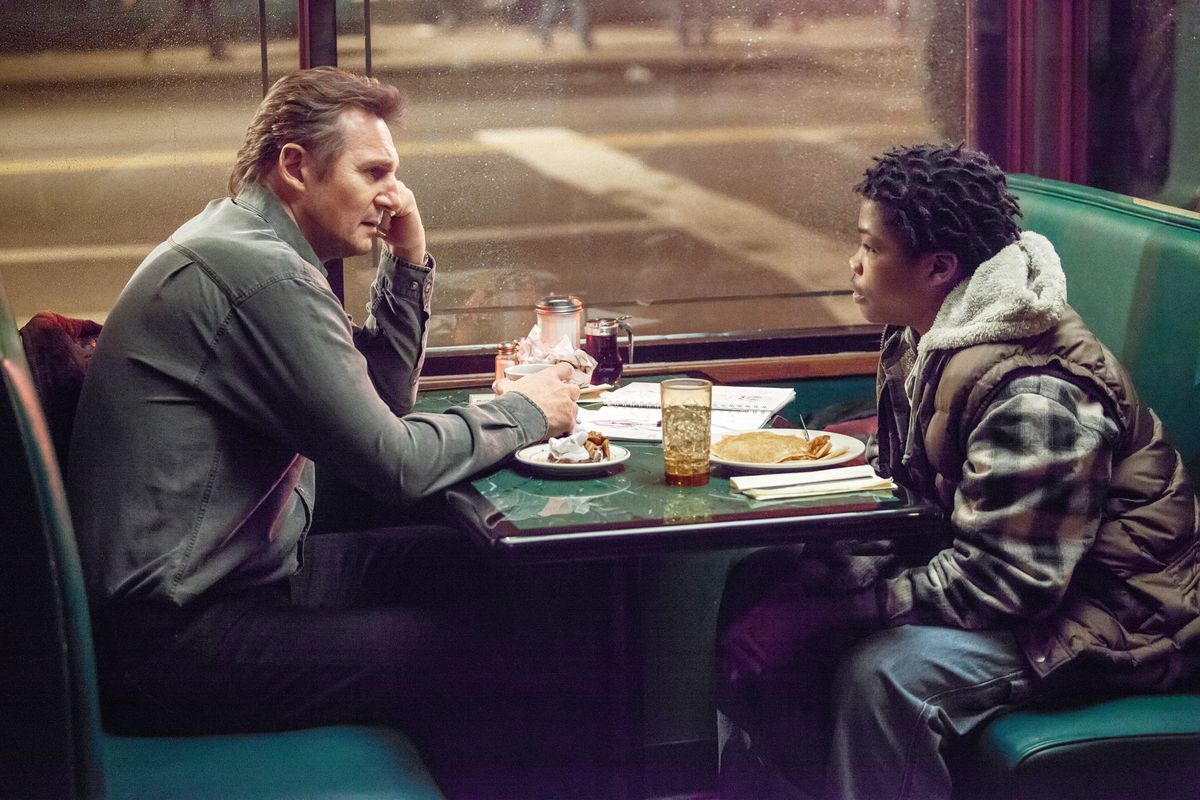 Liam Neeson sits across from Astro in a diner booth in A Walk Among the Tombstones