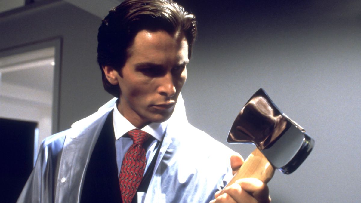 Patrick Bateman (Christian Bale) holds onto an axe while wearing a suit under a plastic poncho in American Psycho