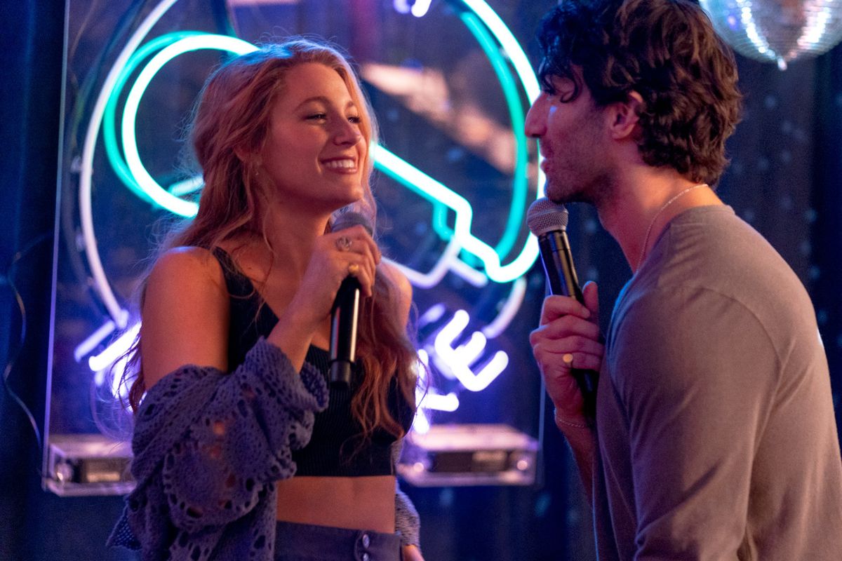 Blake Lively and Justin Baldoni as Lily and Ryle in It Ends With Us. They’re happily doing karaoke together.