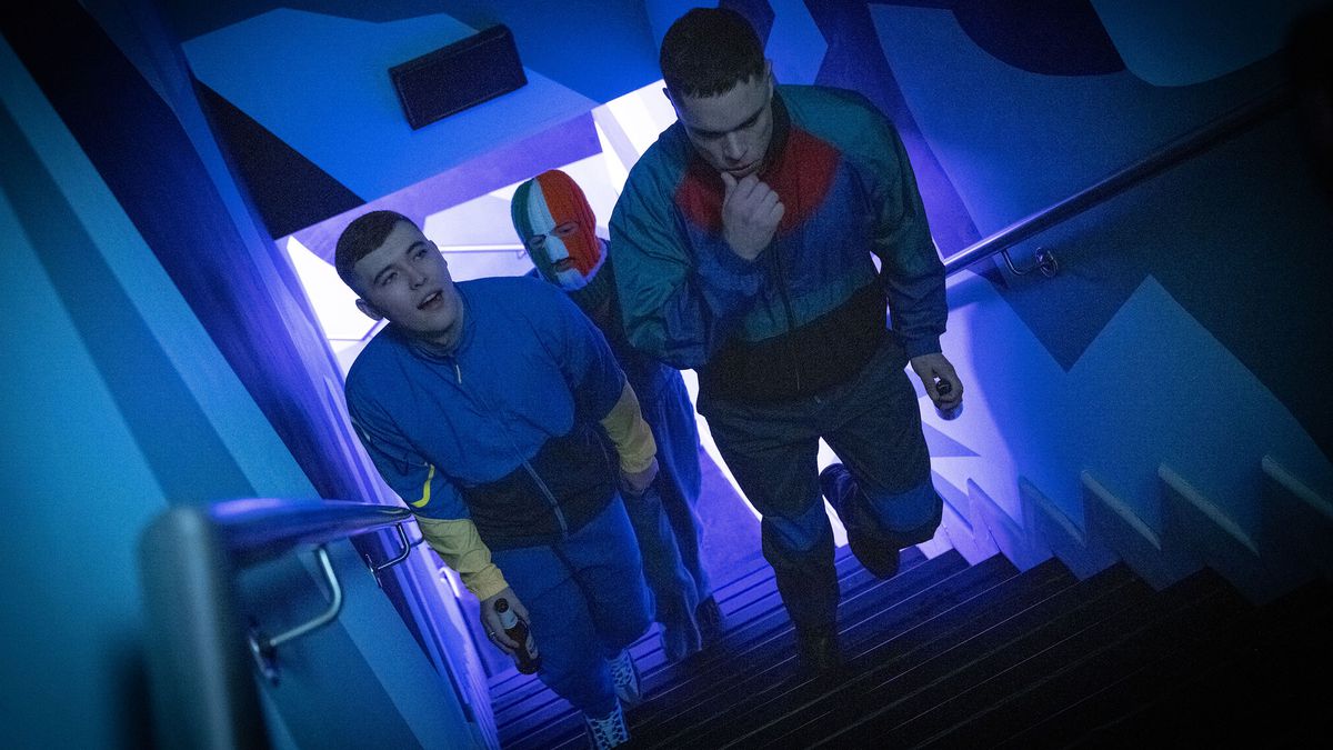 Three young men in matching blue tracks suits walk up some stairs