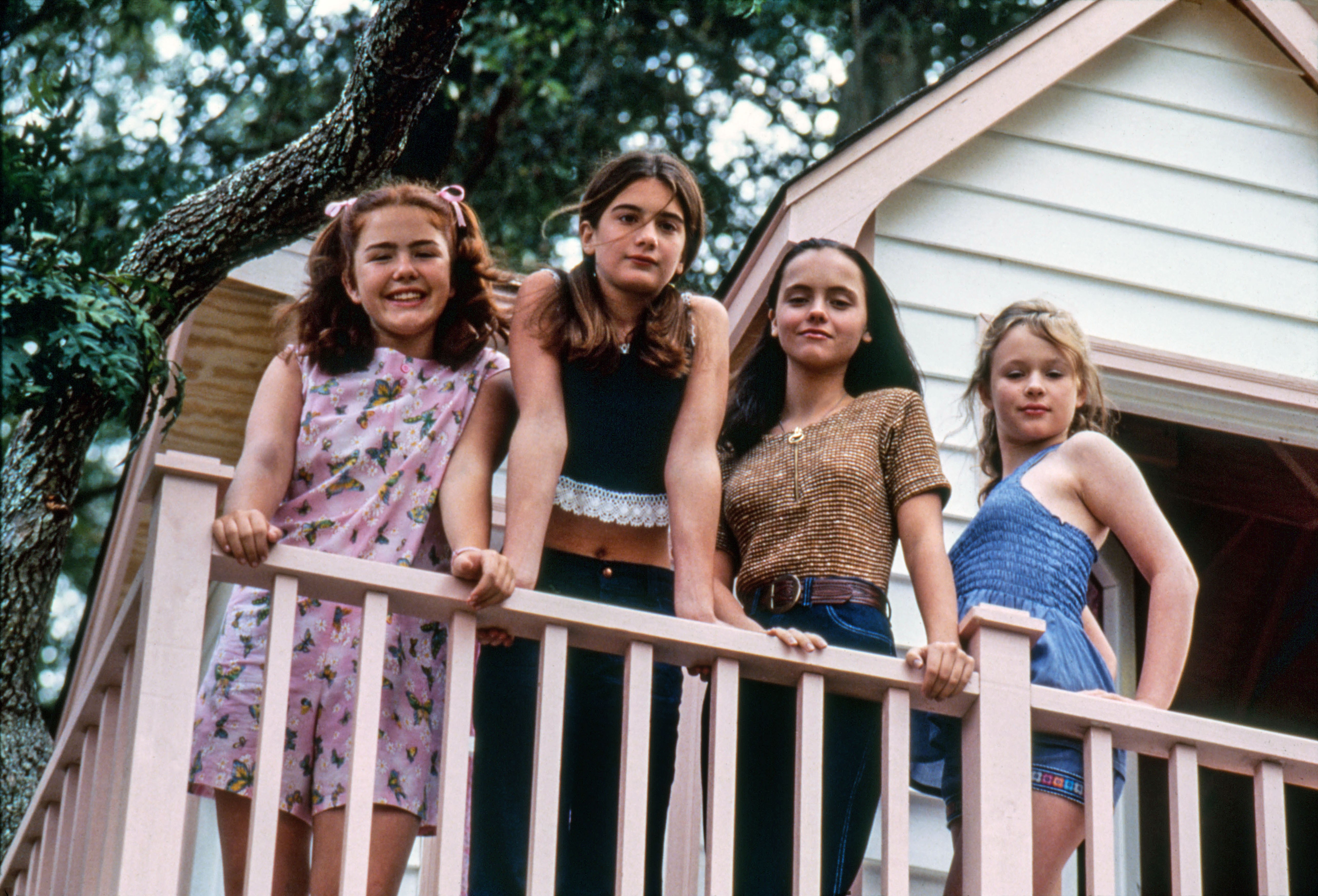 Four girls lean on the banister of a treehouse in Now and Then