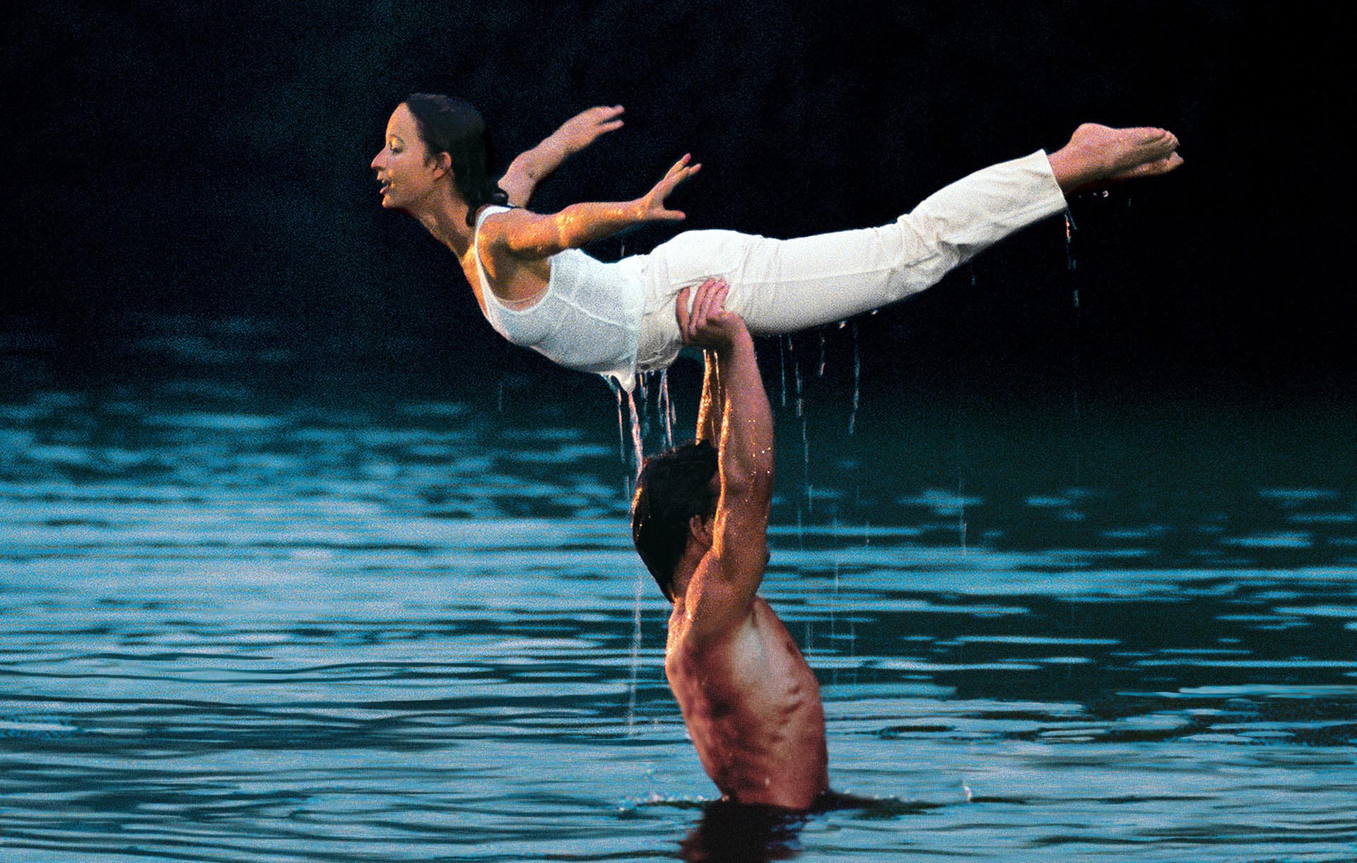 Patrick Swayze shirtless and wet in a lake, holding up Jennifer Grey above his head in Dirty Dancing