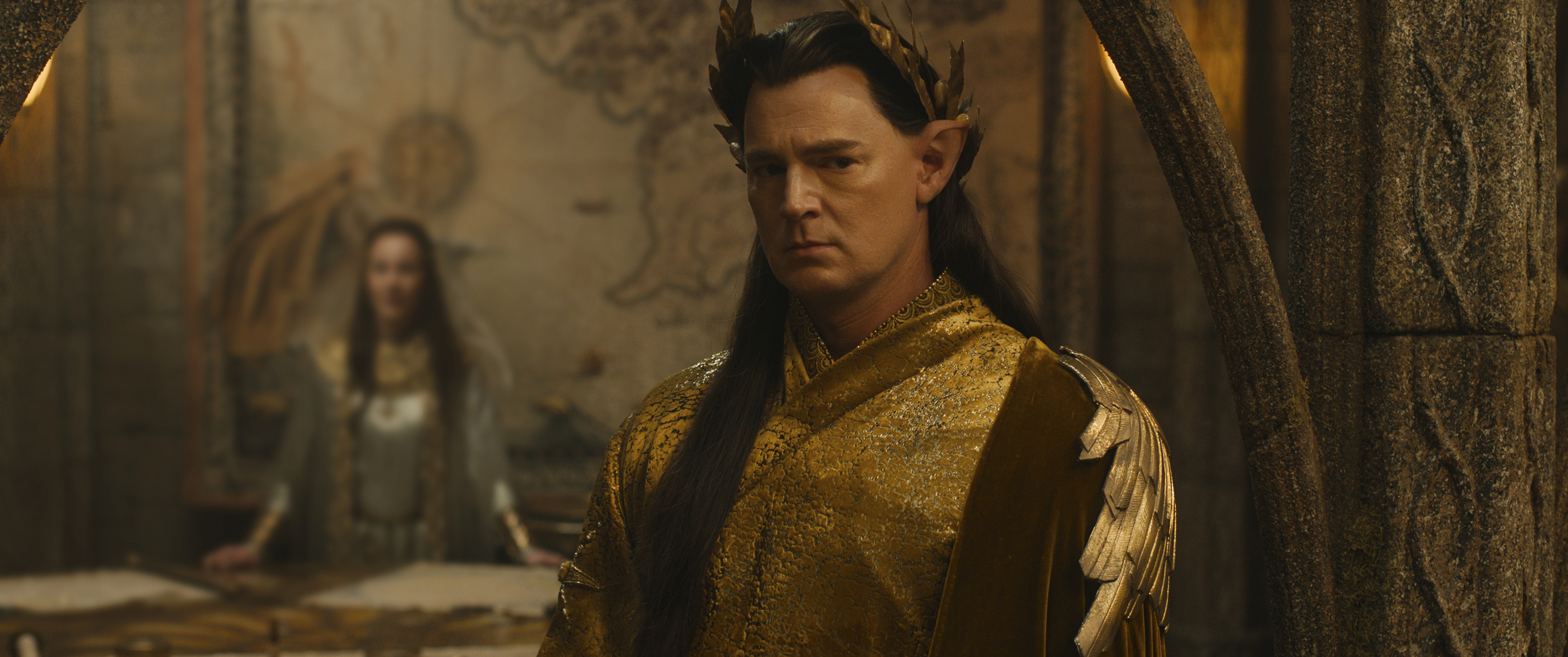 Elven High King Gil-galad (Benjamin Walker), a severe-looking, dark-haired elf in a crown, looks pensive in The Rings of Power