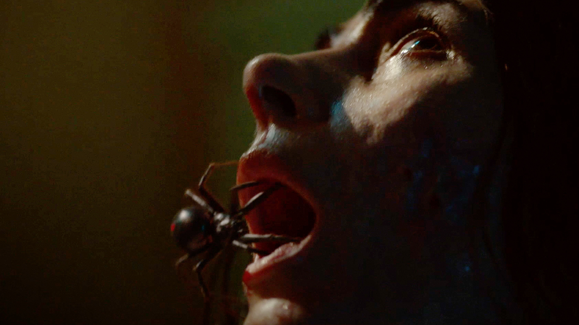 A spider crawling into the month of a woman with tears in her eyes in Sting (2024)