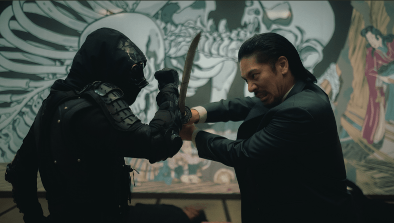 A fight in The Shadow Strays — one man, wearing a suit, has a sword, while another person in all-black armor blocks the sword with their armored forearm