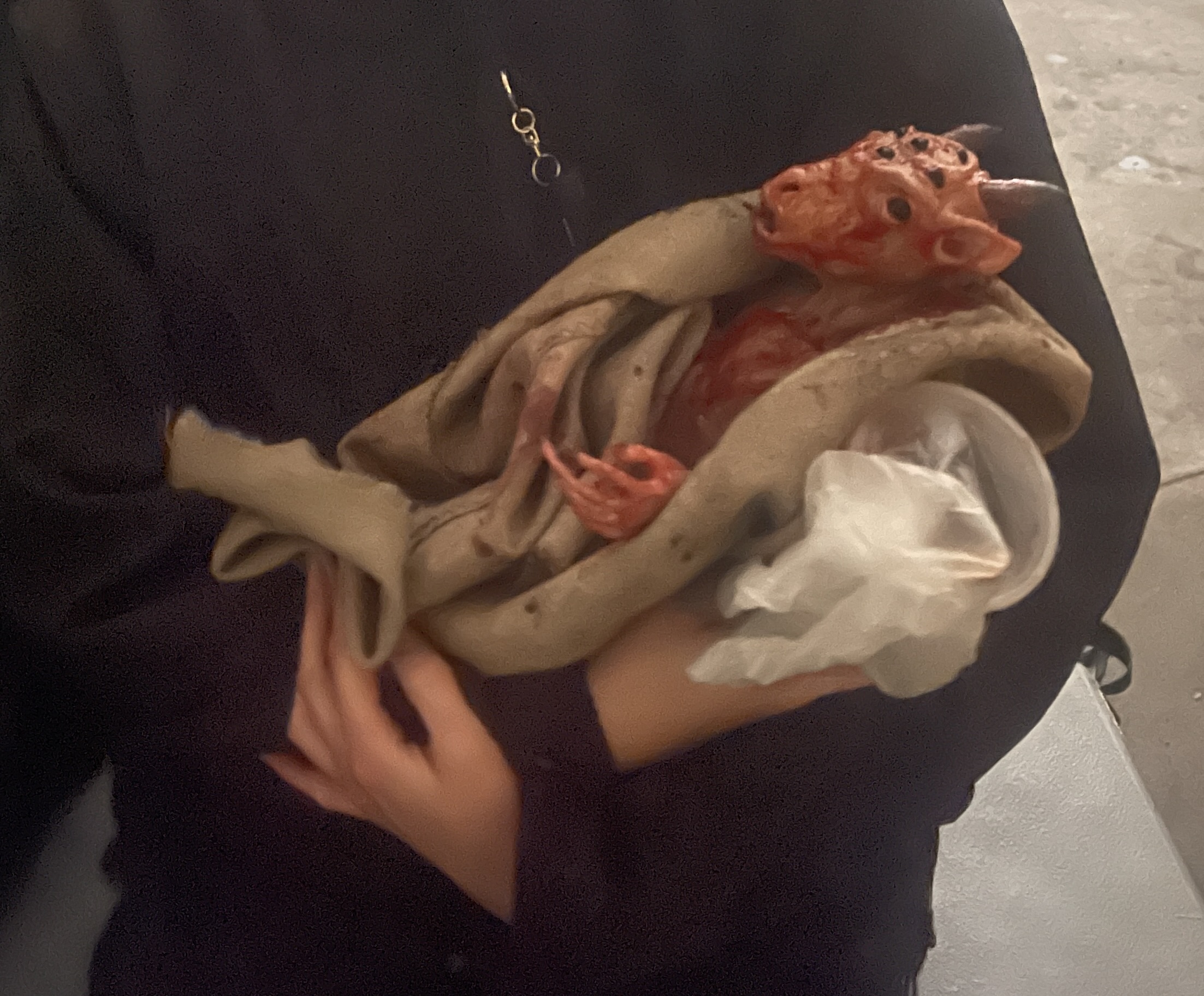 A behind the scenes shot of the baby from the end of Azrael, being cradled by someone in a blanket