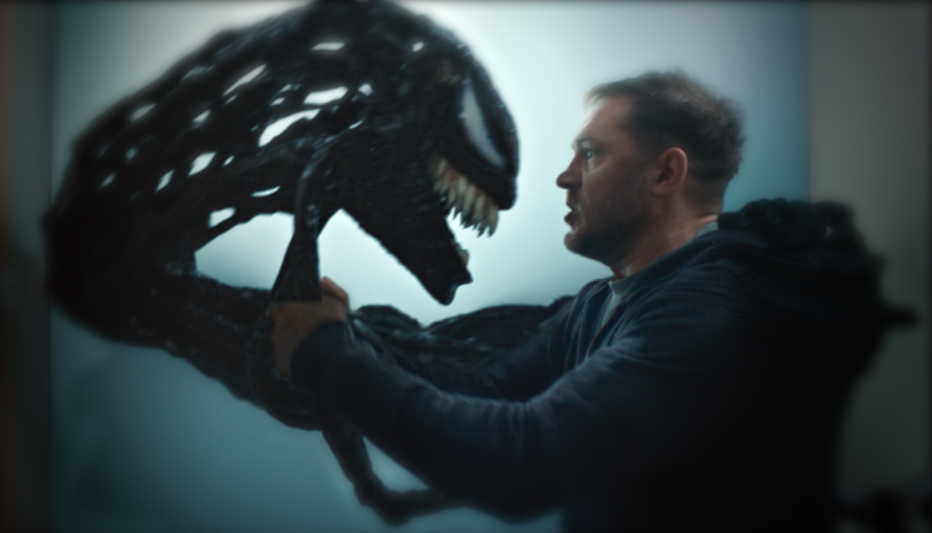 Eddie Brock (Tom Hardy) converses with the Venom symbiote’s gross goo head.