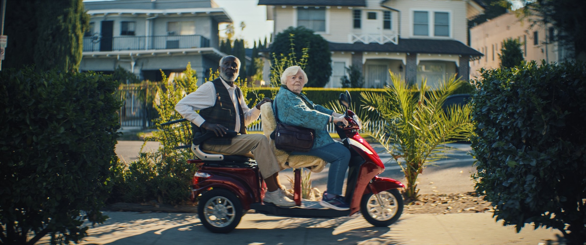 June Squibb and Richard Round Tree as Thelma and Ben, look to their right as they motor down the sidewalk on a two-seater mobility scooter in Thelma.