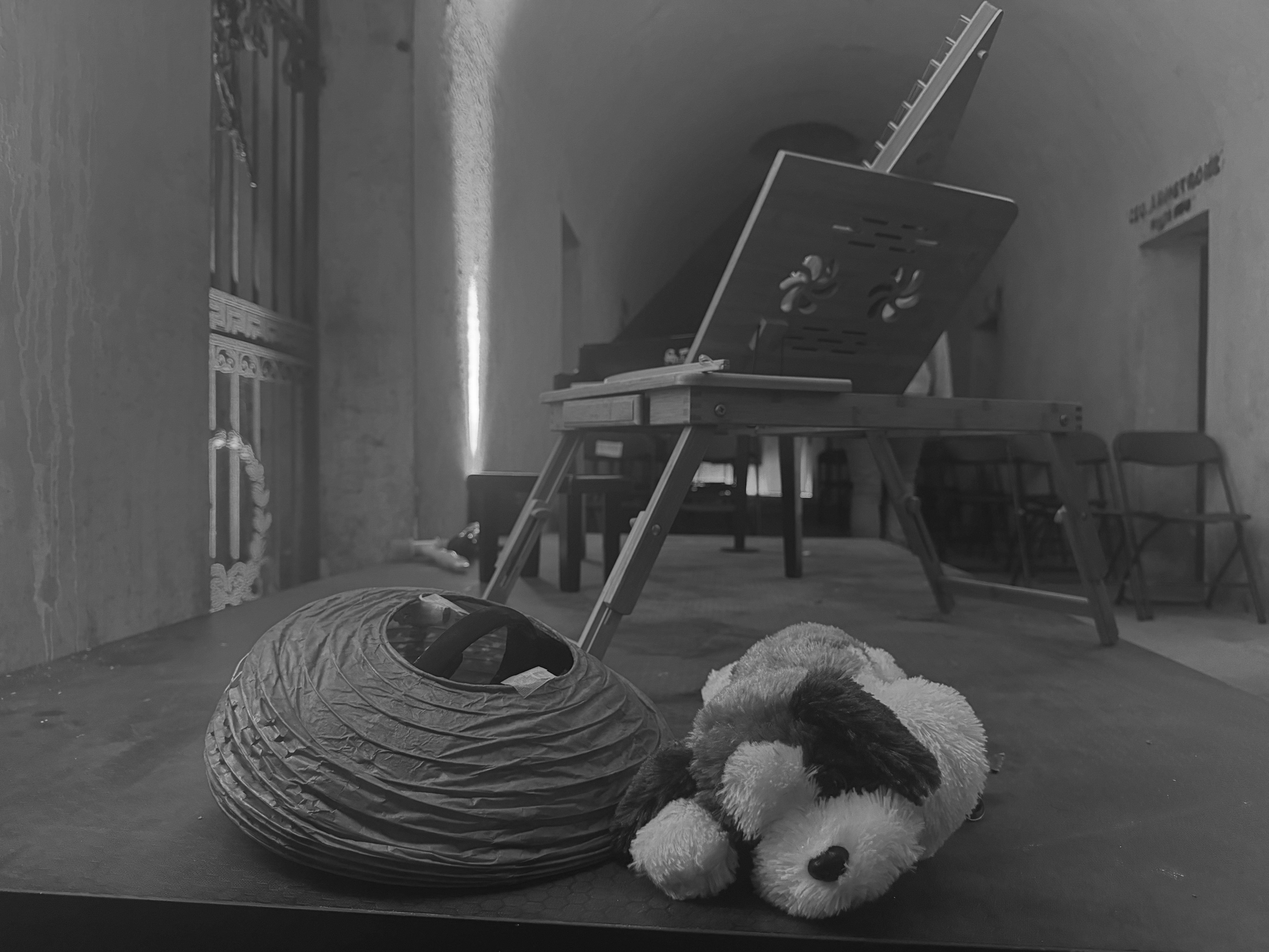 A plush dog and a paper lantern on stage from the October 3, 2024 performance of Curios in the Catacombs by Margaret Leng Tan at Green-Wood Cemetery in New York