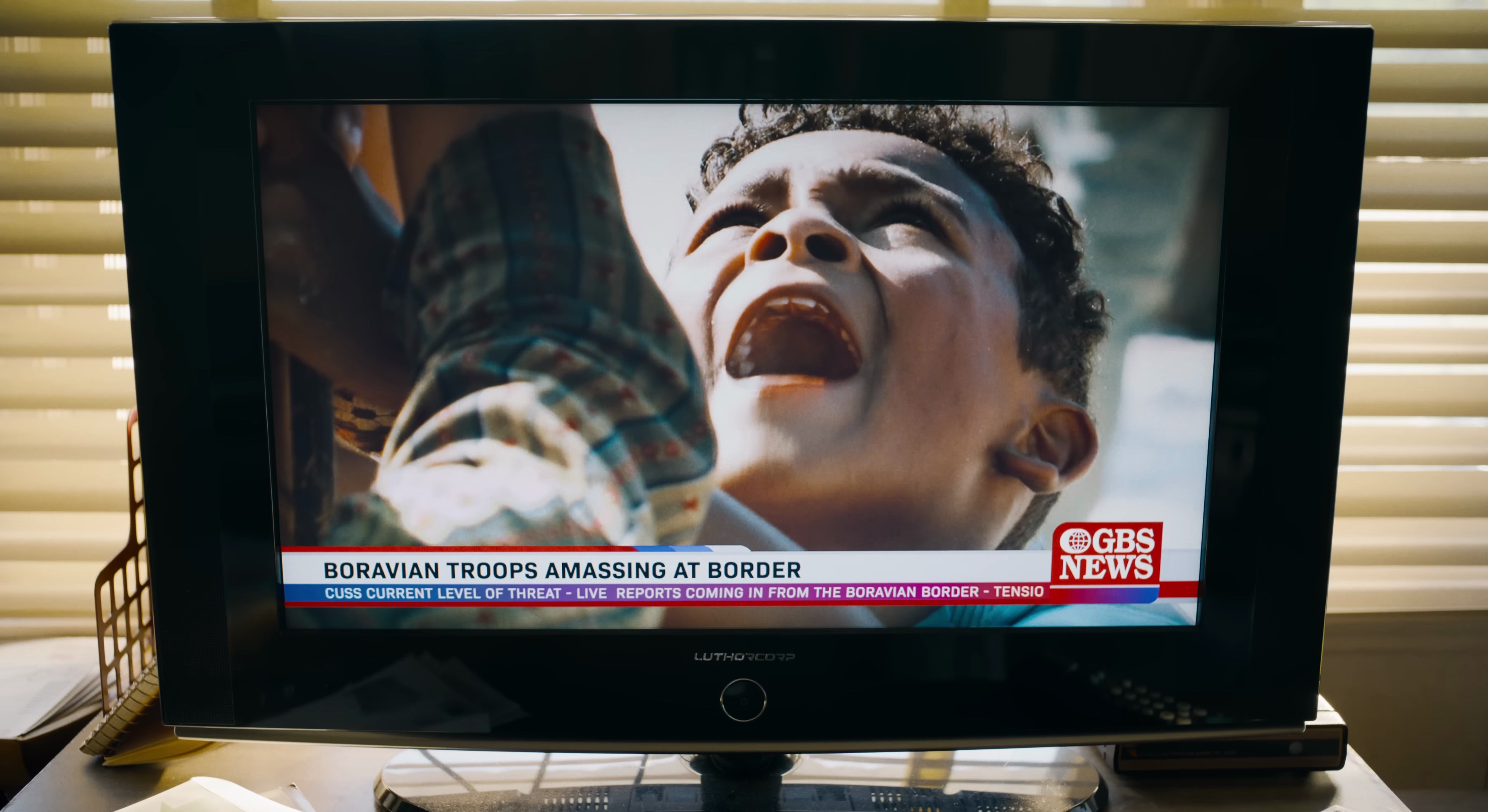 A child yells on a TV with a chyron saying Boravian troops have amassed at the border in Superman 2025