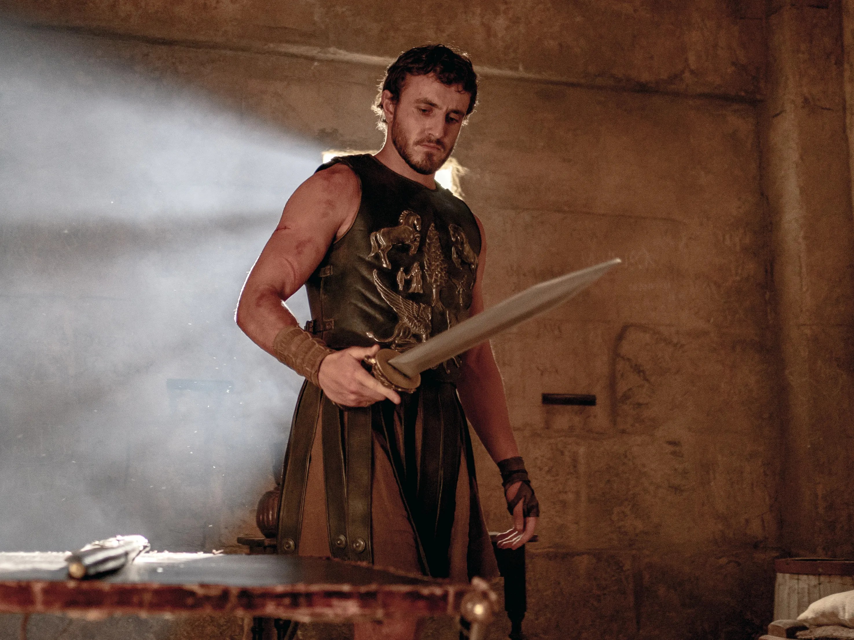 Paul Mescal in gladiatorial armor holding a sword in Gladiator II