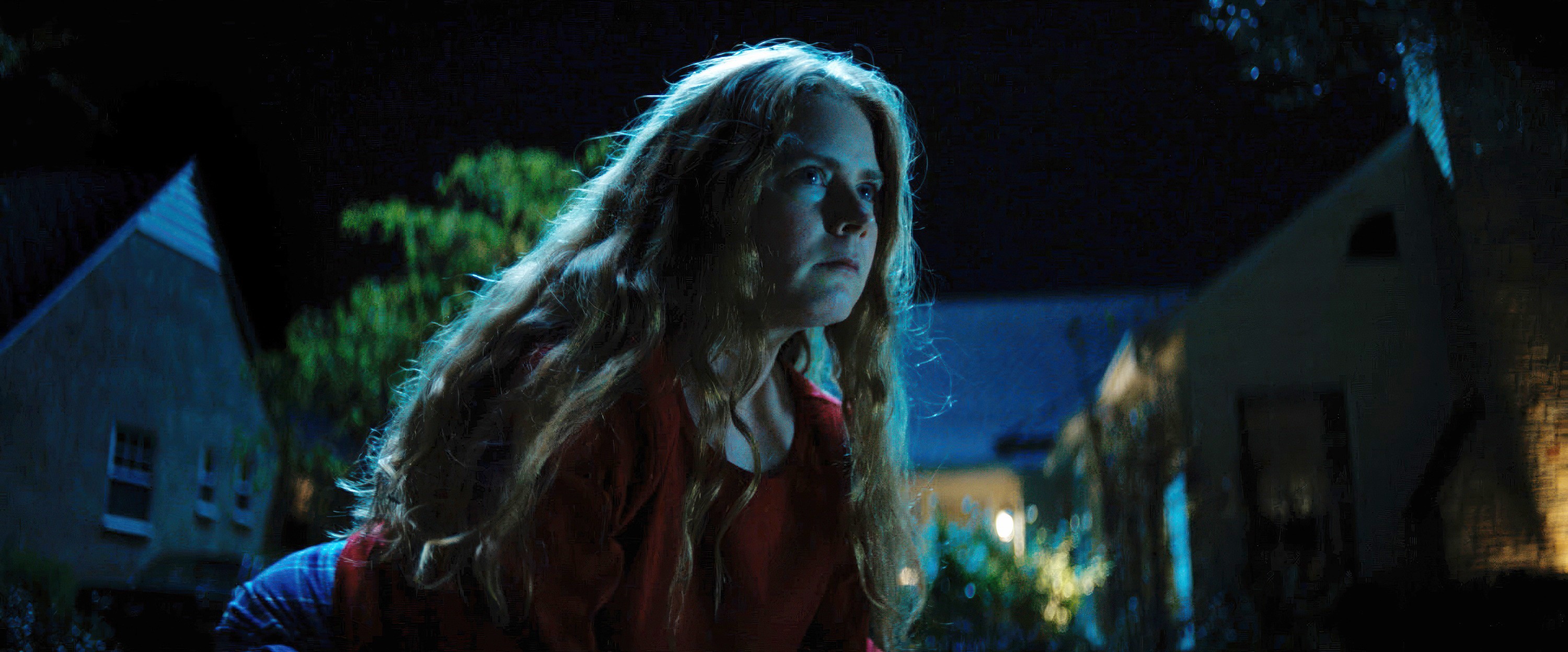 Mother (Amy Adams) looks determined and feral as she looms in a night shot outdoors in Nightbitch