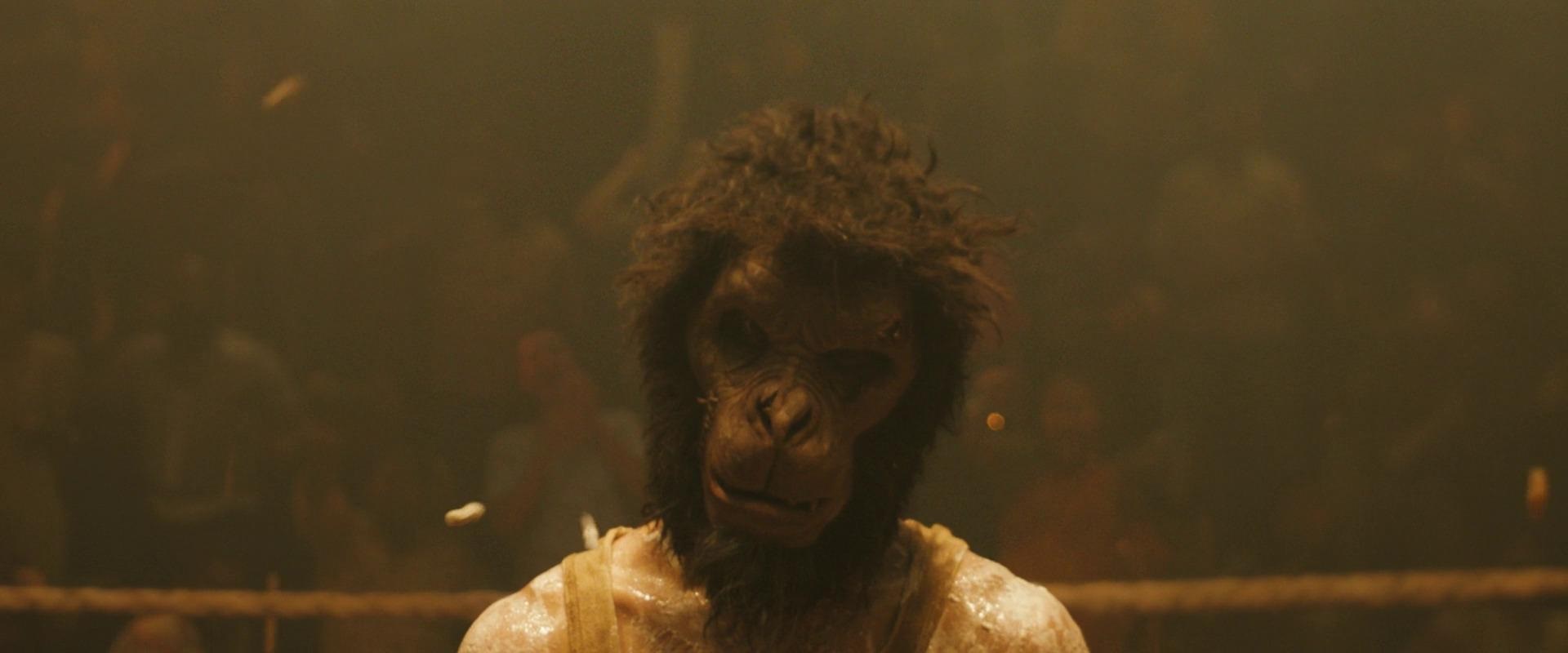 A man wearing a monkey mask looks at the camera in Monkey Man