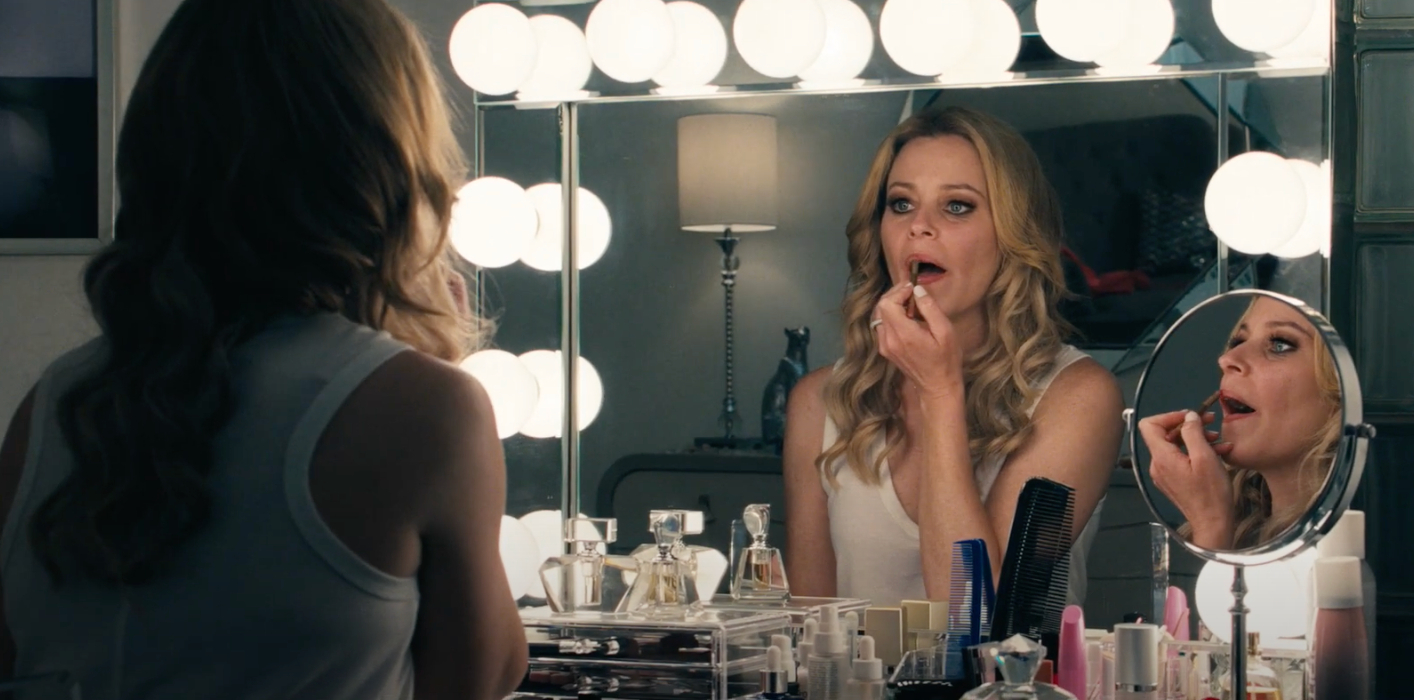 Elizabeth Banks applying makeup in a mirror in Skincare