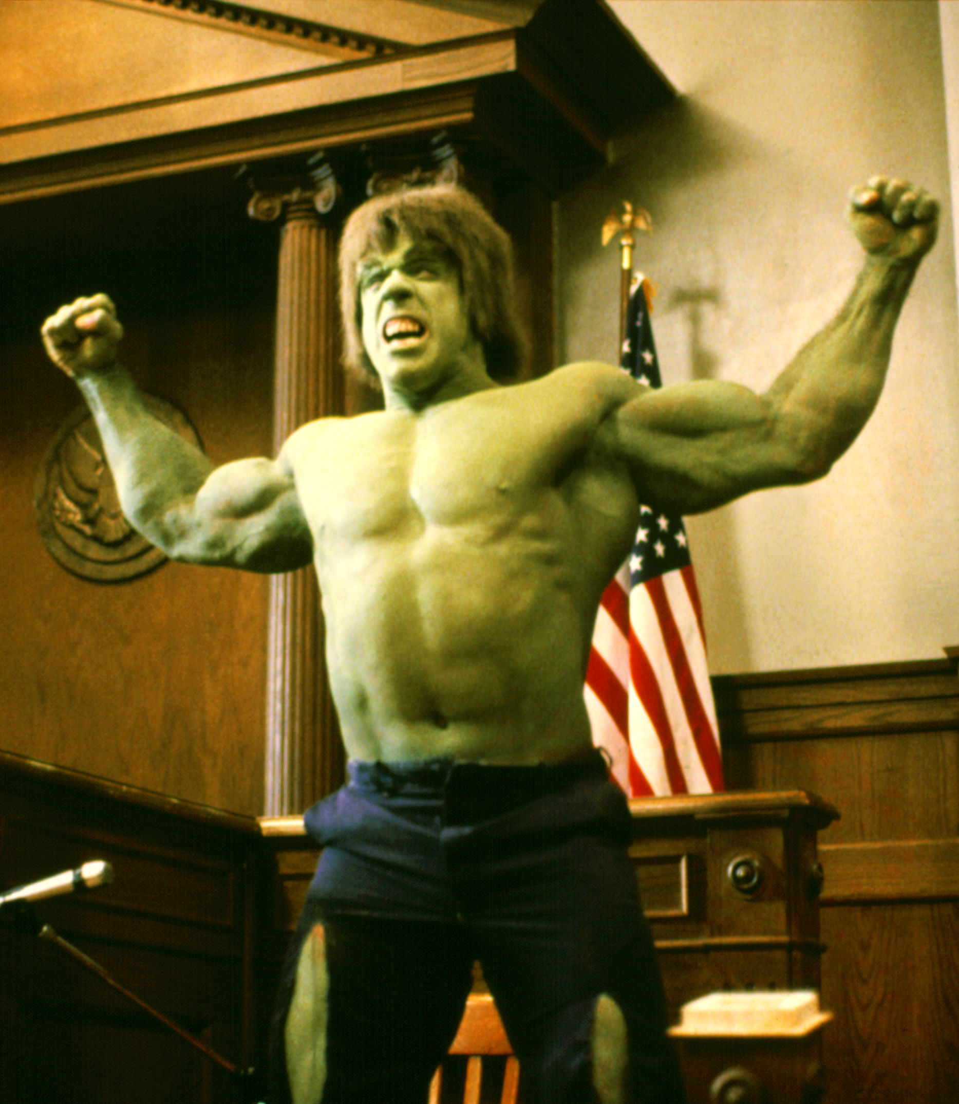 Hulk flexes in a court room in front of the American flag in The Trial of the Incredible Hulk