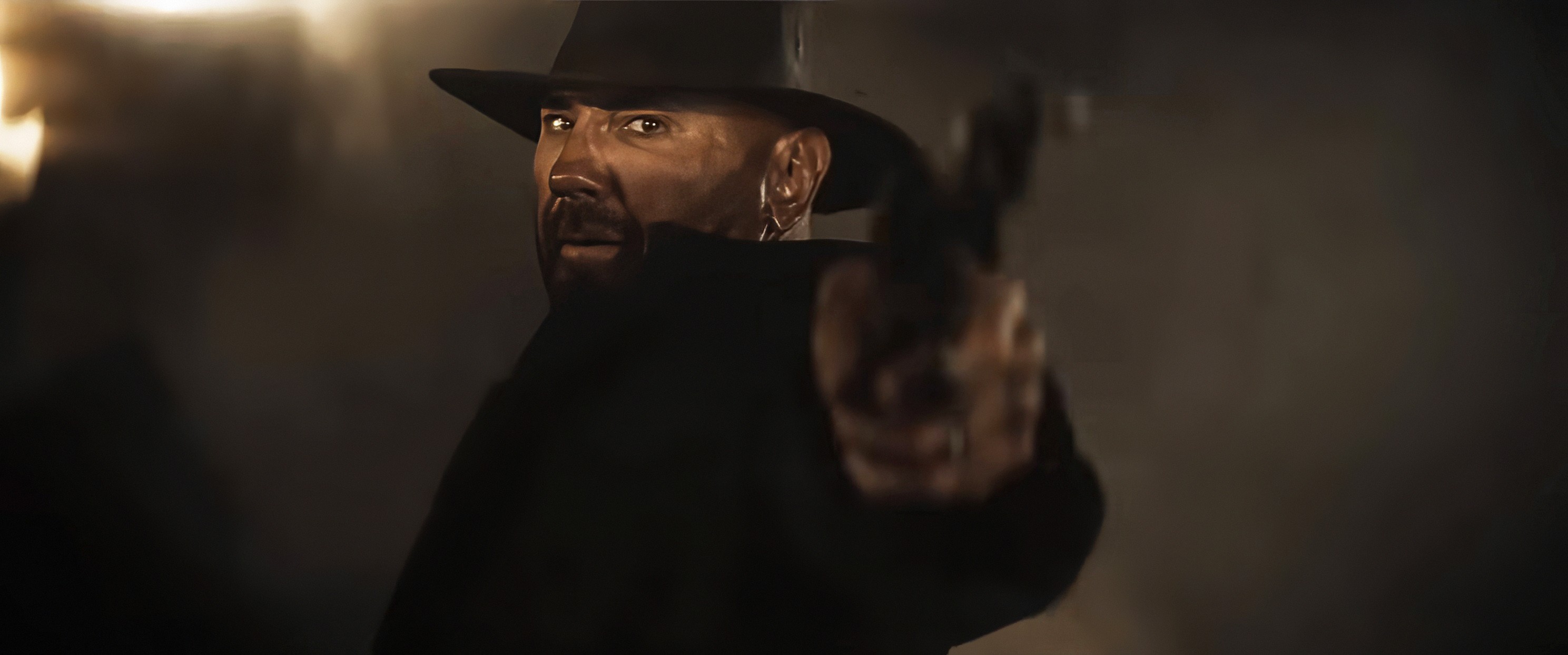 Dave Bautista in cowboy hat and holding a revolver pointed at the camera in In the Lost Lands