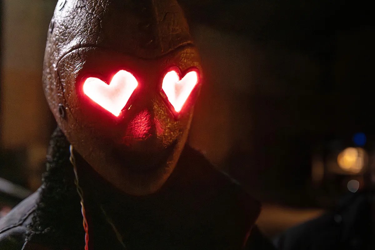 A masked figure with glowing heart-shaped eyes in Heart Eyes.