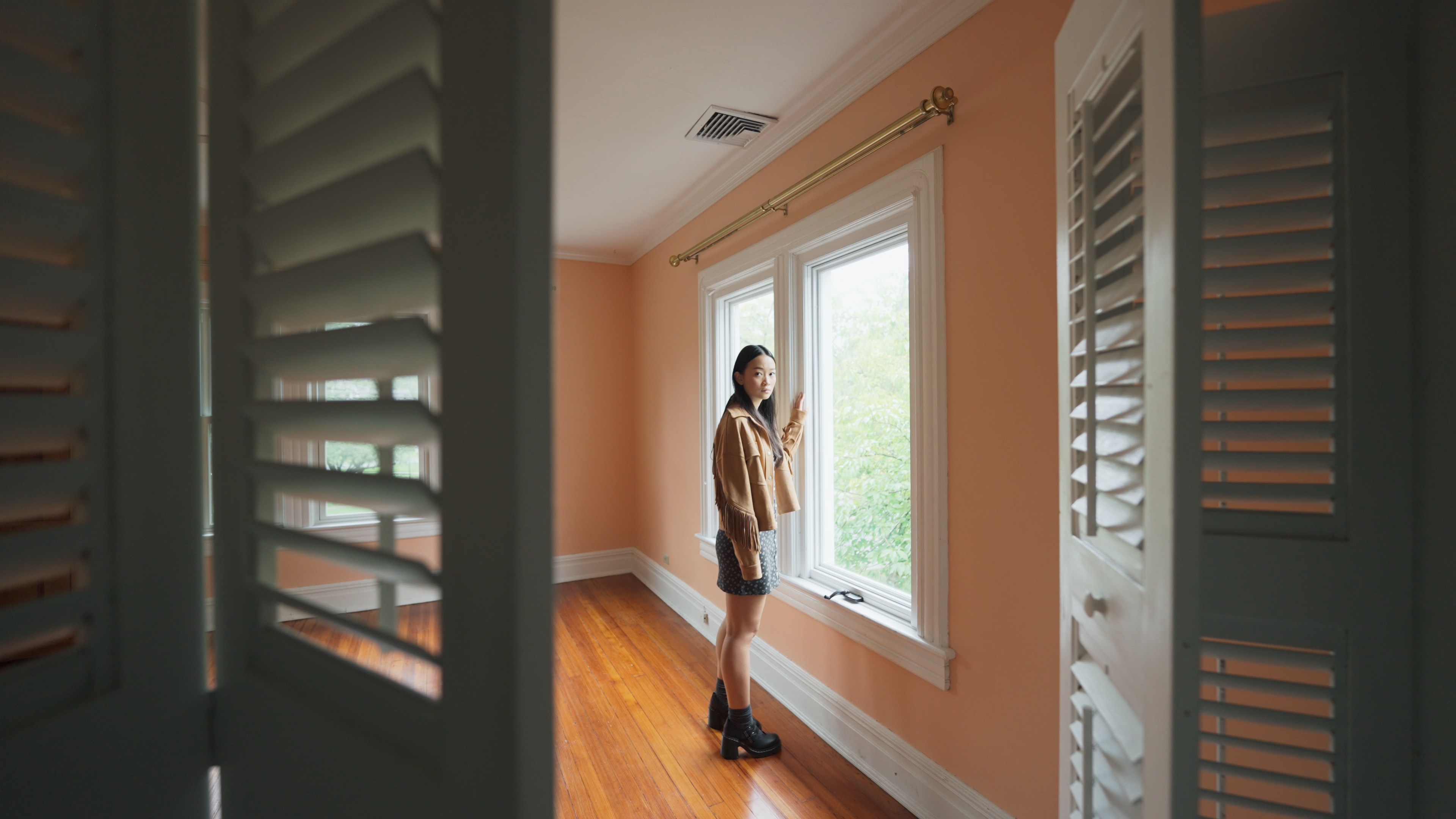 Chloe (Callina Liang), a forlorn-looking teenager, stands by a window in an unfurnished room and looks at the closet, where an unseen presence lurks in Presence