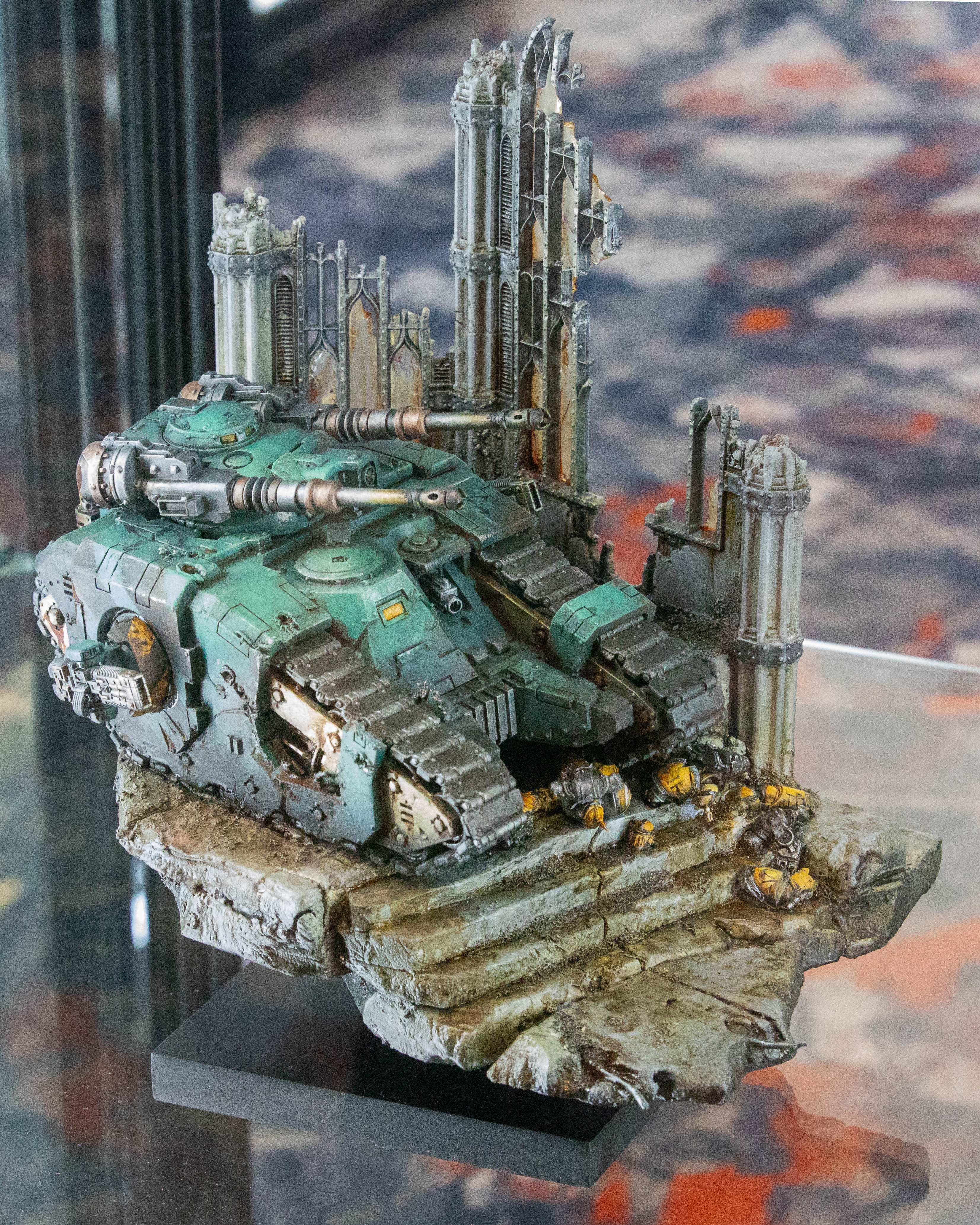 A tank rolls past a ruined cathedral in this miniature Warhammer 40K model