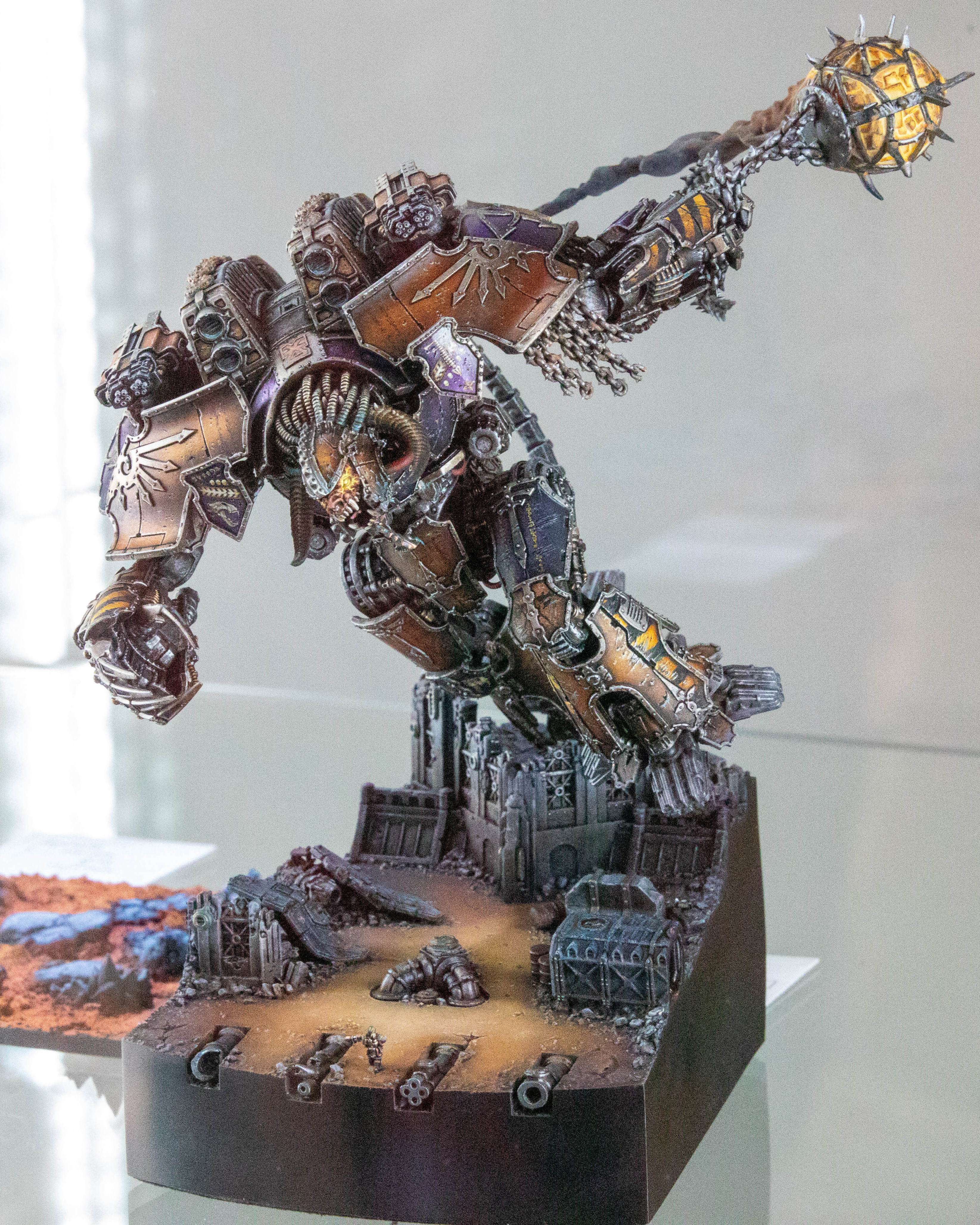 A model showing a chaos titan leaning down to hit a tiny figure