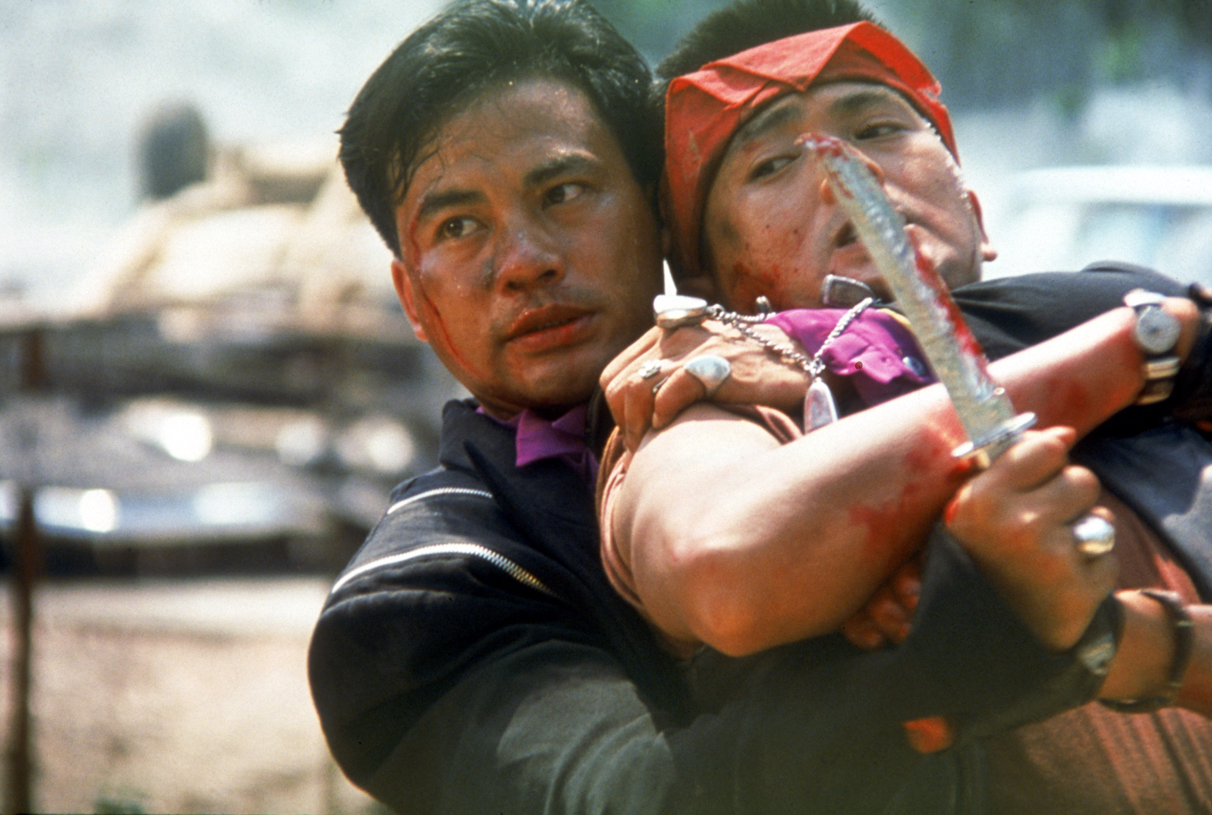 In Full Contact, Simon Yam holds a knife and grabs tightly onto a struggling Chow Yun-fat