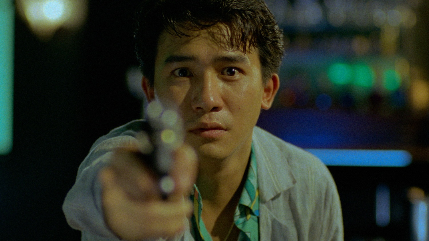 Tony Leung Chiu-wai holds a gun towards the camera in My Heart is That Eternal Rose