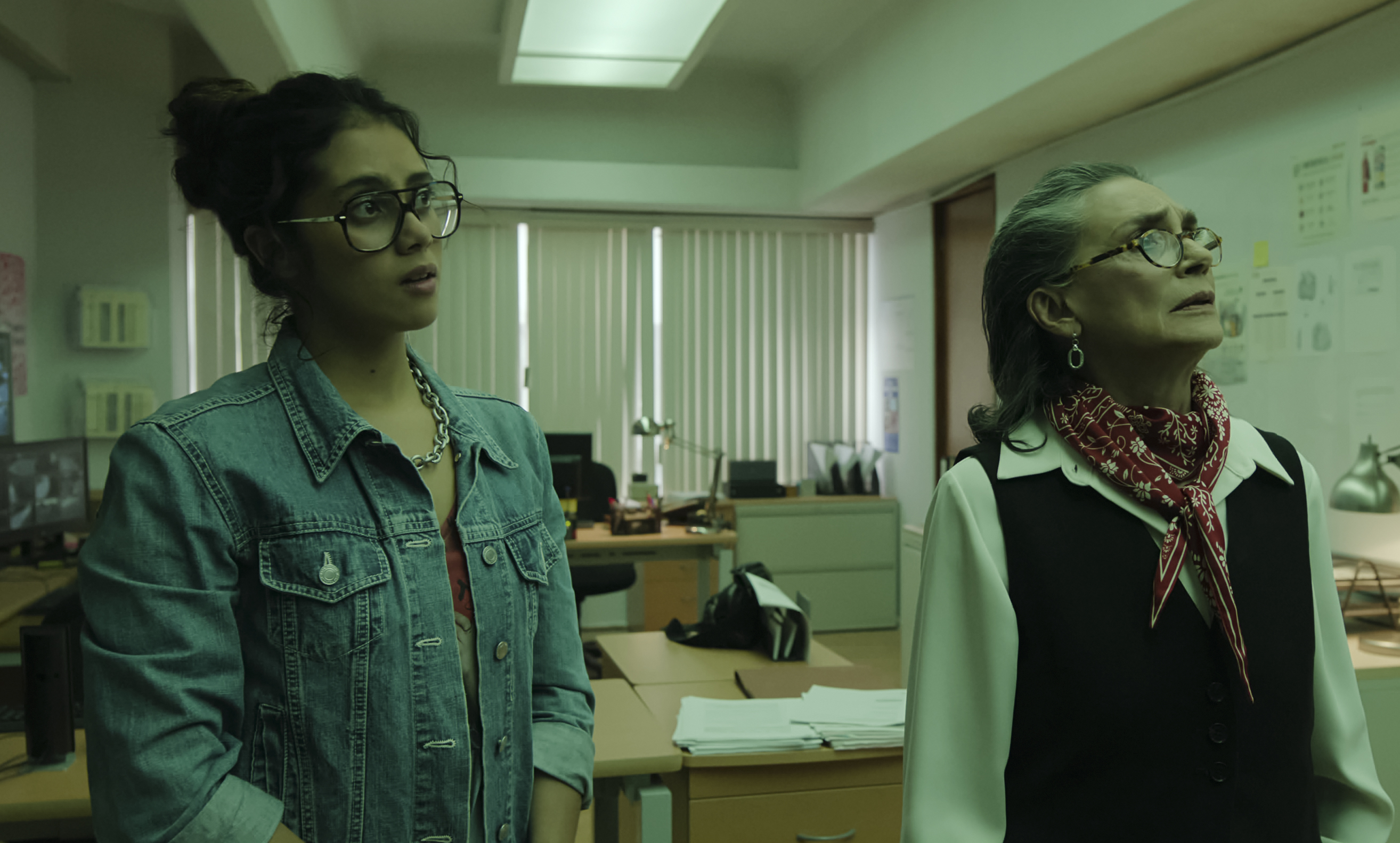 Renata Vaca as Alondra and Ofelia Medina as Julia look concerned standing in an academic office at the National Autonomous University of Mexico in Our Times.