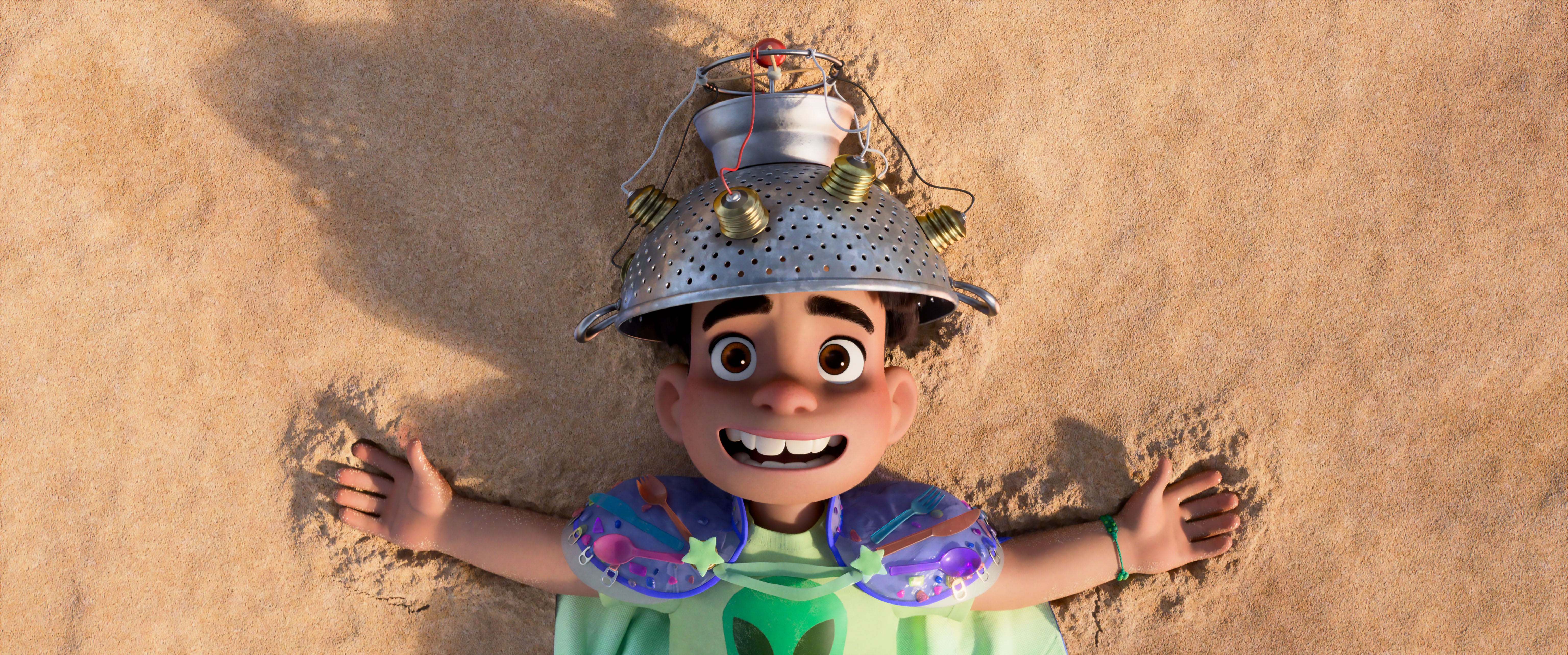 Elio lays on the beach with a helmet made out of a collander