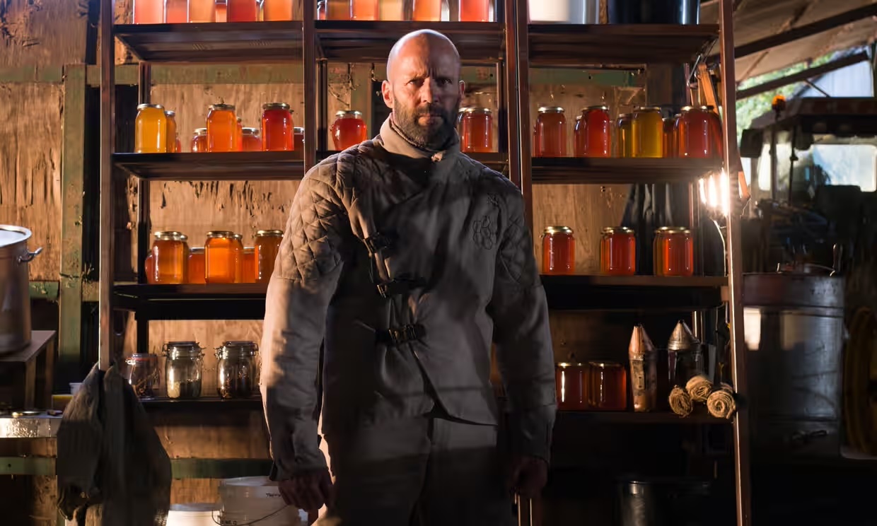A beekeeper (Jason Statham) stands in front of some honey in The Beekeeper