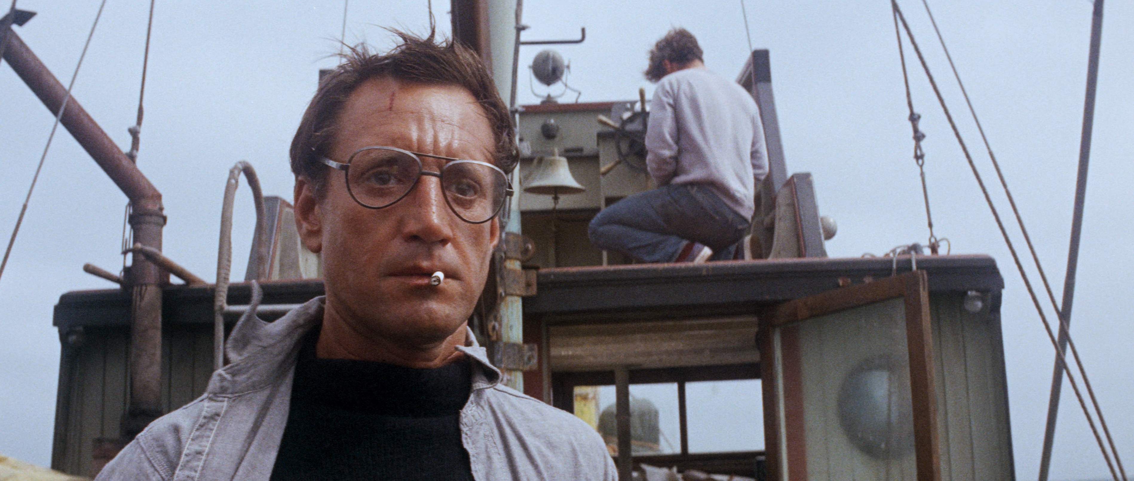 Roy Scheider as Police Chief Brody wearing big glasses and smoking a cigarette, stares in shock at the back end of a boat in Jaws